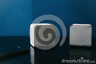 Wireless speakers and a cell phone next to them on a dark background. Modern technology for listening to music from a Stock Photo