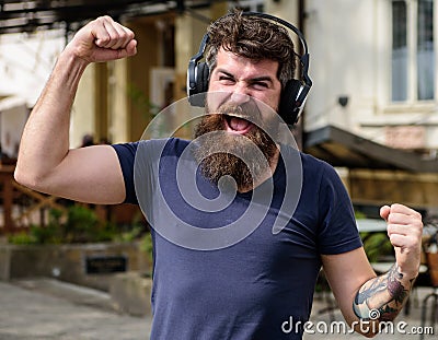 Wireless technologies concept. Hipster with headphones on happy face listening music while walking. Man with long beard Stock Photo