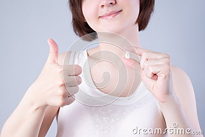 Wisdom teeth extraction, happy woman with tooth in hand on gray background Stock Photo