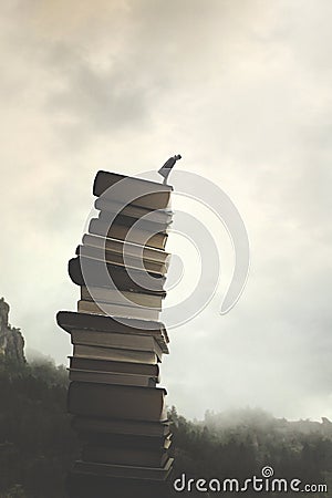 Wise and successful man looks down from the top of a surreal pile of books Stock Photo