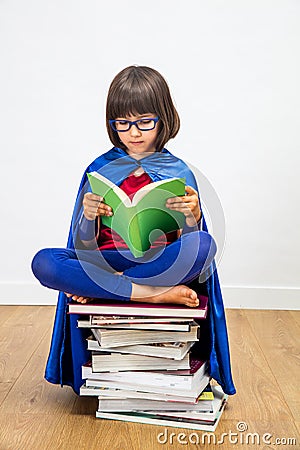 Wise schoolgirl with super hero costume reading for girl power Stock Photo