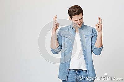 Wishful religious man with hopeful expression gesturing with fingers. Unshaven dark-haired guy in denim clothes closing Stock Photo