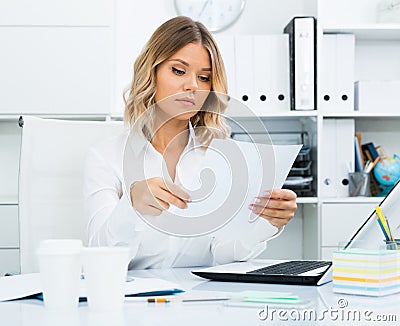 Wistful young woman in white shirt in bright office Stock Photo