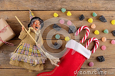 The witch Befana and red stocking with sweet coal and candy on rustic wooden background. Italian Epiphany day tradition Stock Photo