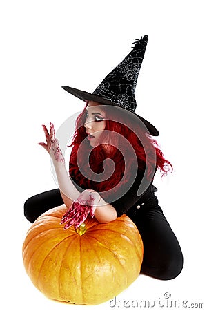 Witch with bloodstained hands with a hatchet in hand sits on a p Stock Photo