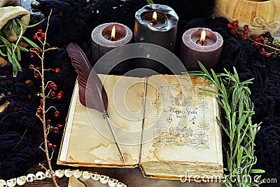 Witch book of spells with black candles on altar table. Stock Photo