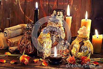 Witch bottles, black candles and roses agains planks with pentagram Stock Photo