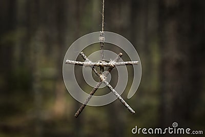 Witchcraft sticks symbol. Magic occult symbol. Totem hanging on tree in dark forest. Stock Photo