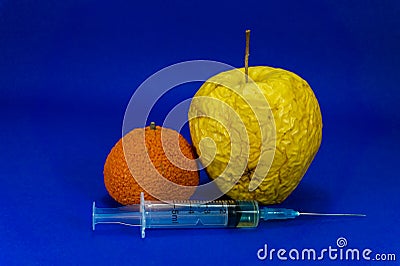 Withered orange and apple with hypodermic needle Stock Photo