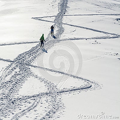 Two skiers come up the slope. One does it on skis and the other goes with skis fastened to the backpack. Editorial Stock Photo