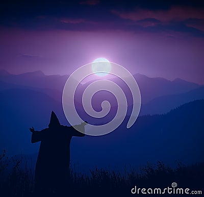 Wizard standing on a hill and welcome rising of the moon Stock Photo