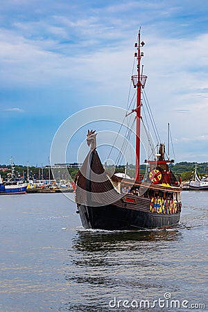 Beautiful wooden viking boat Rakkar with decorations around full of tourists at Baltic sea at Editorial Stock Photo