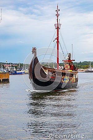 Beautiful wooden viking boat Rakkar with decorations around full of tourists at Baltic sea at Editorial Stock Photo