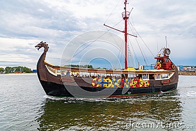 Beautiful wooden viking boat Rakkar with decorations around full of tourists at Baltic sea at Editorial Stock Photo