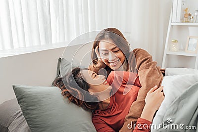 Wo young women spend time next to each other, lying on the bed and laughing Stock Photo
