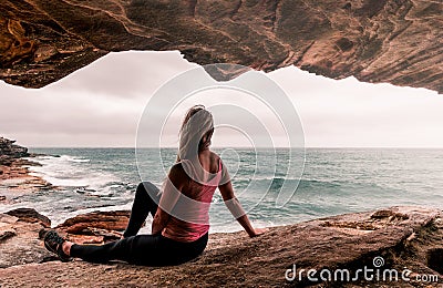 Woman in activewear sitting by the ocean Stock Photo