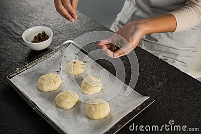 Woman adding dry fruits over unbaked cookie dough Stock Photo