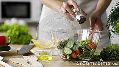 Woman adding salt in vegetable salad glass bowl, health care, excessive salting Stock Photo