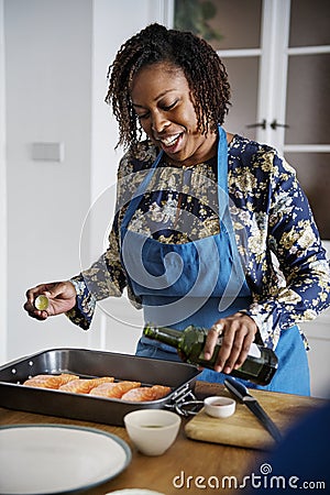 Woman adding spices and herb to raw salmon Stock Photo