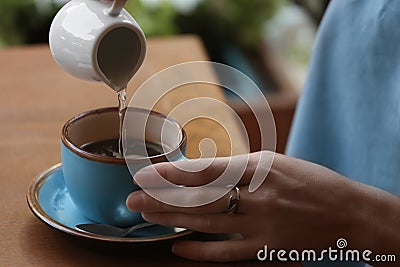 Woman adding water to fresh aromatic coffee at table Stock Photo