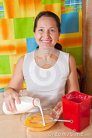 Woman adds milk into dish Stock Photo