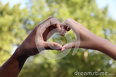 Woman and African American man making heart with hands outdoors, closeup Stock Photo