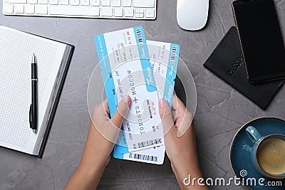 Woman with airline tickets at grey table, top view. Travel agency concept Stock Photo