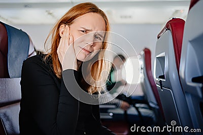 a woman on an airplane has a headache and an earache while flying on an airplane Stock Photo