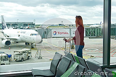 Woman at the airport window and flight departure, Airport Terminal: Happy Traveling Looks Around. Frankfurt am Main Editorial Stock Photo