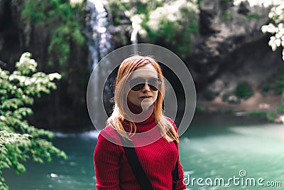 Woman alone sitting, motorcyclists travelers. travel nature Forests, mountains, beautiful waterfall on background. summer day. Stock Photo