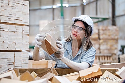 woman American African wearing safety uniform and hard hat working quality inspection of wooden products at workshop manufacturing Stock Photo