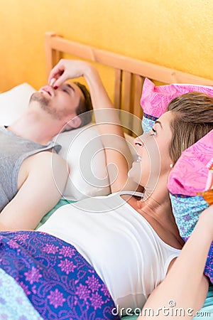 Woman is angry and holds nose of her snoring partner Stock Photo