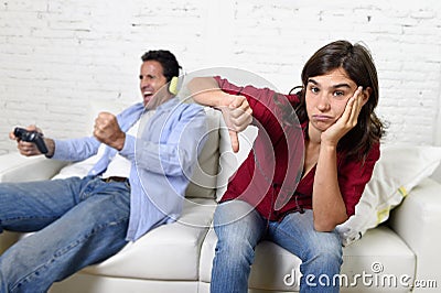 Woman angry and upset while husband or boyfriend plays videogames ignoring her Stock Photo