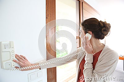 Woman answering door security phone Stock Photo