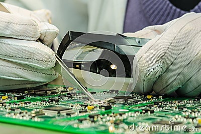 Woman in antistatic gloves holding pincette and magnifier Stock Photo