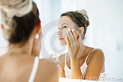 Woman applying face cream in bathroom Stock Photo