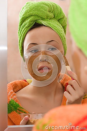 Woman applying facial mask from brown clay Stock Photo