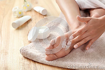 Woman applying foot cream on towel, closeup. Stock Photo