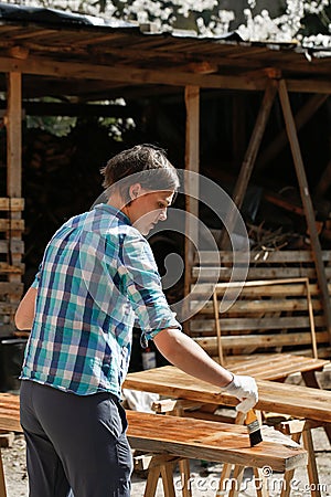 Woman applying fresh wood treatment paint Stock Photo