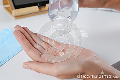 Woman applying hand sanitizer at white table, closeup. Personal hygiene during COVID-19 pandemic Stock Photo