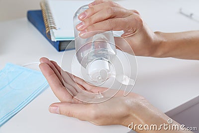 Woman applying hand sanitizer at white table in office, closeup. Personal hygiene during COVID-19 pandemic Stock Photo