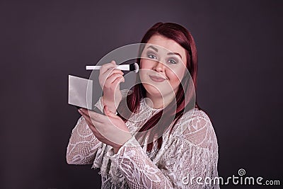 Woman applying makeup with brush holding compact mirror Stock Photo