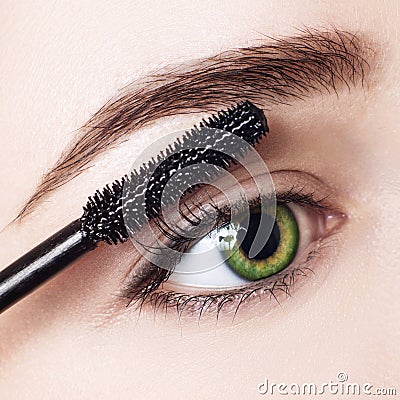 Woman applying mascara on eyelashes with brush. Stock Photo