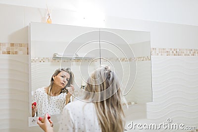 Woman applying morning make up in bathroom`s mirror Stock Photo