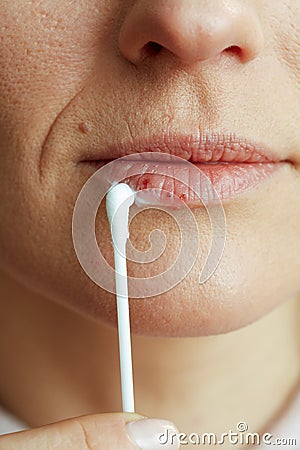 Woman applying ointment using cotton swab on beige Stock Photo