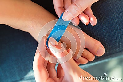 Woman applying sticking plaster to little child`s foot; close up view Stock Photo