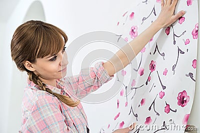 Woman applying wallpaper on wall in new house Stock Photo