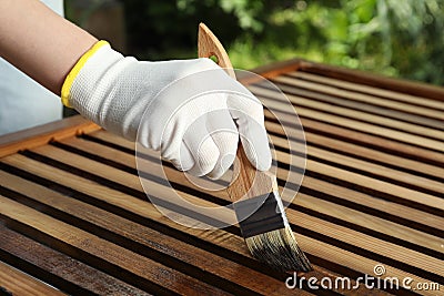 Woman applying wood stain onto planks outdoors, closeup Stock Photo
