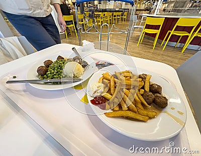 Woman Approaches IKEA Dining: Fries, Meatballs and Peas Editorial Stock Photo