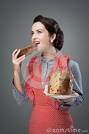 Woman in apron eating panettone Stock Photo